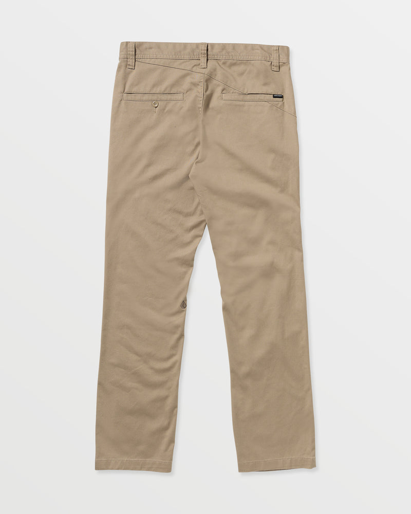 The Men’s Frickin Modern Stretch Pants by Volcom are shown from the back in tan khaki, featuring two back pockets, belt loops, and a straight leg cut. Crafted from recycled polyester for sustainable comfort, these modern pants are displayed against a plain white background.