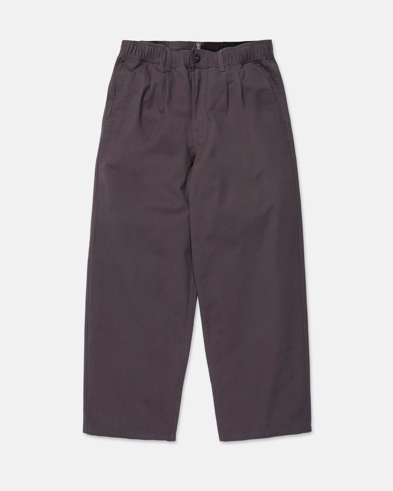 Volcom Men's Chillow Pleat Elastic Waist Pants in dark gray cotton twill, featuring a wide-leg silhouette, elastic waistband with button closure, and side pockets, laid flat on a white background.