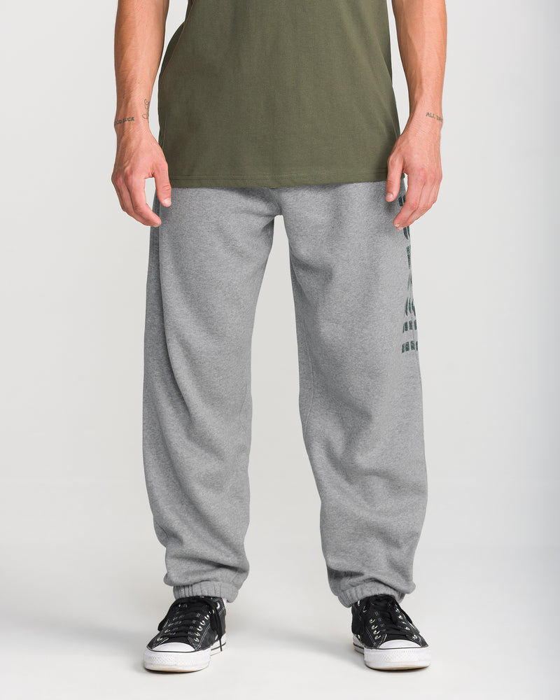 Wearing Men’s Quadratic Fleece Pant by Volcom and black Volcom sneakers, a person stands against a plain background, with only their lower half shown.