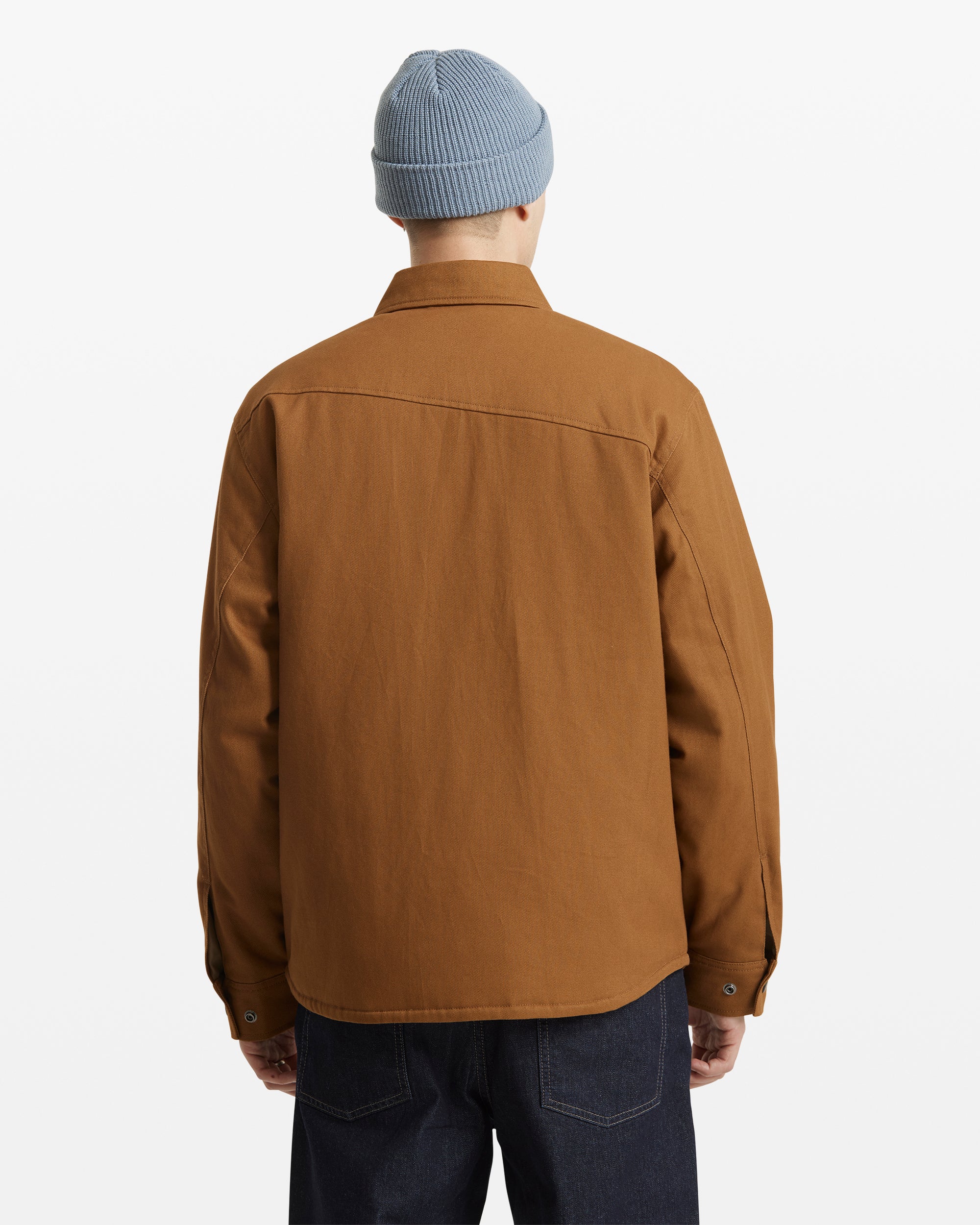 A person is shown from the back against a plain white background, wearing dark jeans, a light blue knit beanie, and the Volcom Men's Westmead Jacket in brown.