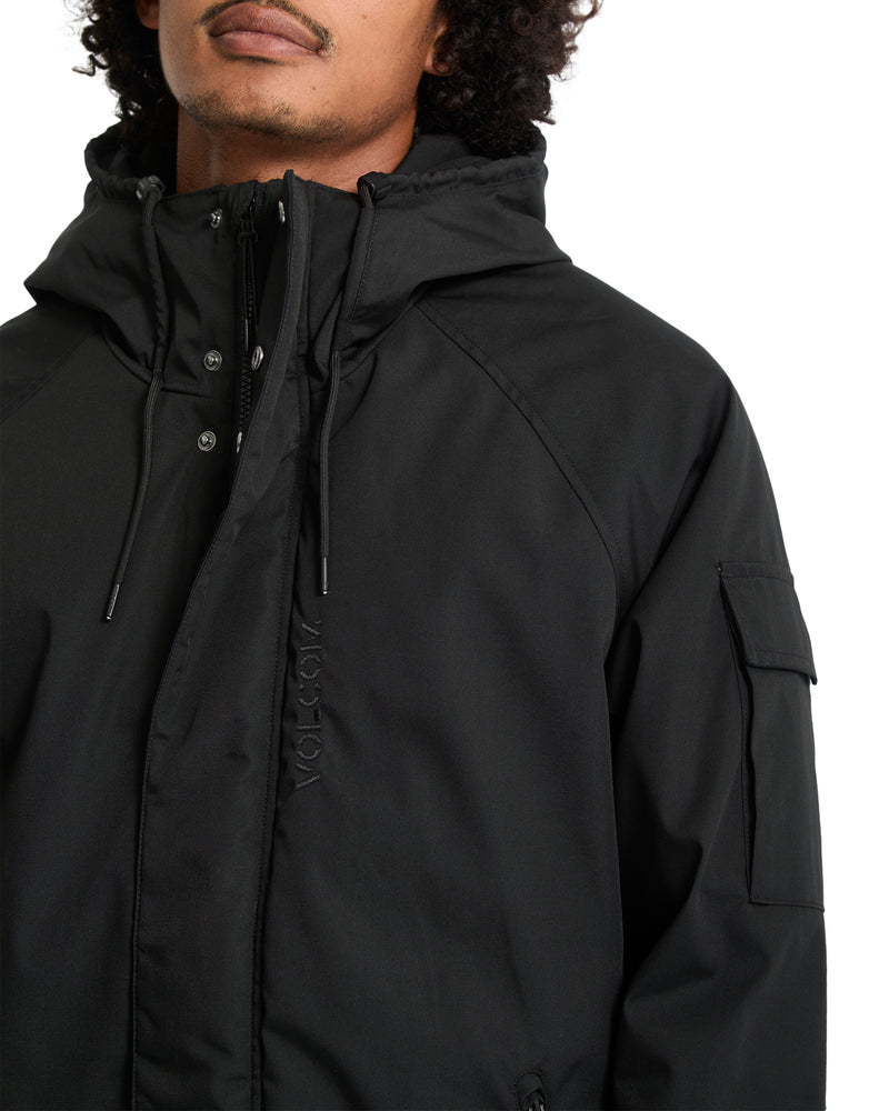 A man wears a Volcom Men’s Stoke Stone II 10K Jacket, a water-resistant hooded winter coat featuring a front zipper, a storm flap with snap closures, and a flap pocket on the left sleeve.