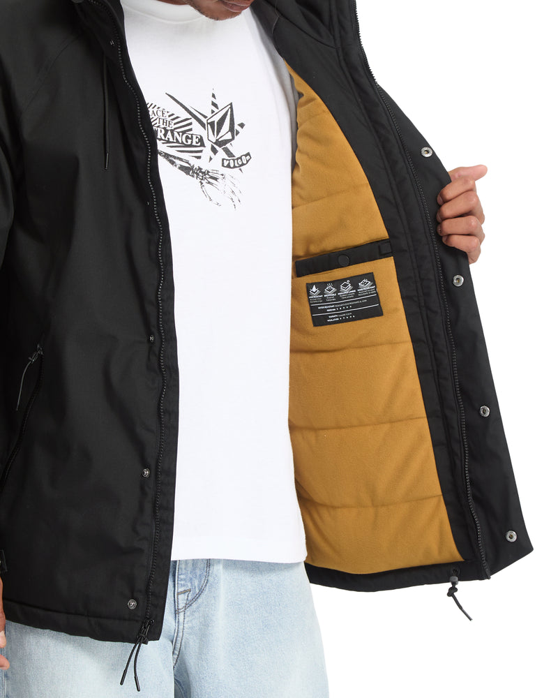 A person wearing a black Volcom Men’s Stoke Stone II 10K Jacket with a gold-colored interior lining, a hood, and an internal chest pocket.