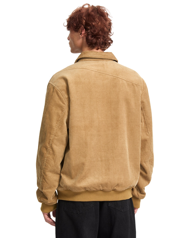 A person seen from the back wearing a tan cotton corduroy Men’s Kurtis Jacket by Volcom with a blouson fit, a collared neckline, and a ribbed hem.