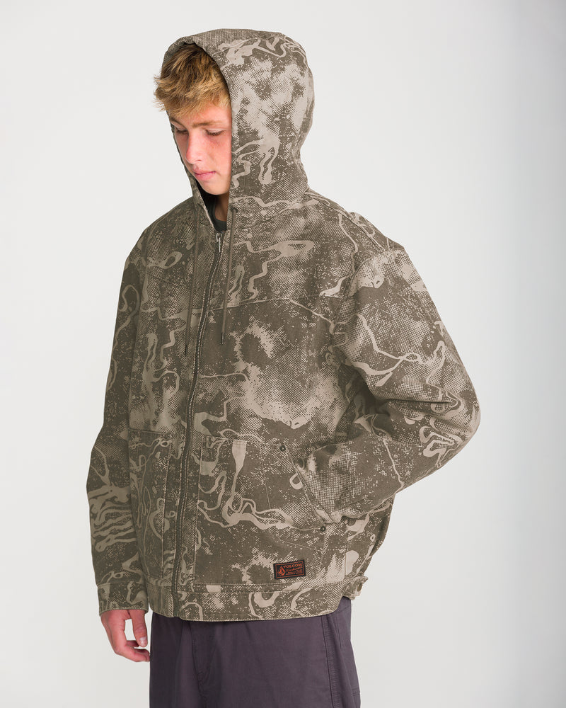A person wearing a Volcom Men’s Fresh Storm Workwear Jacket in tan and brown marbled camo, featuring a zip-up hooded design and a small patch near the bottom hem.