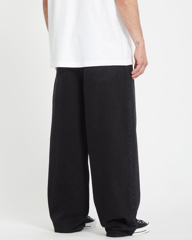 A person wearing a white t-shirt and loose-fitting Men's Chillow Denim jeans in black stands with their back to the camera, showing only the lower half of their body.