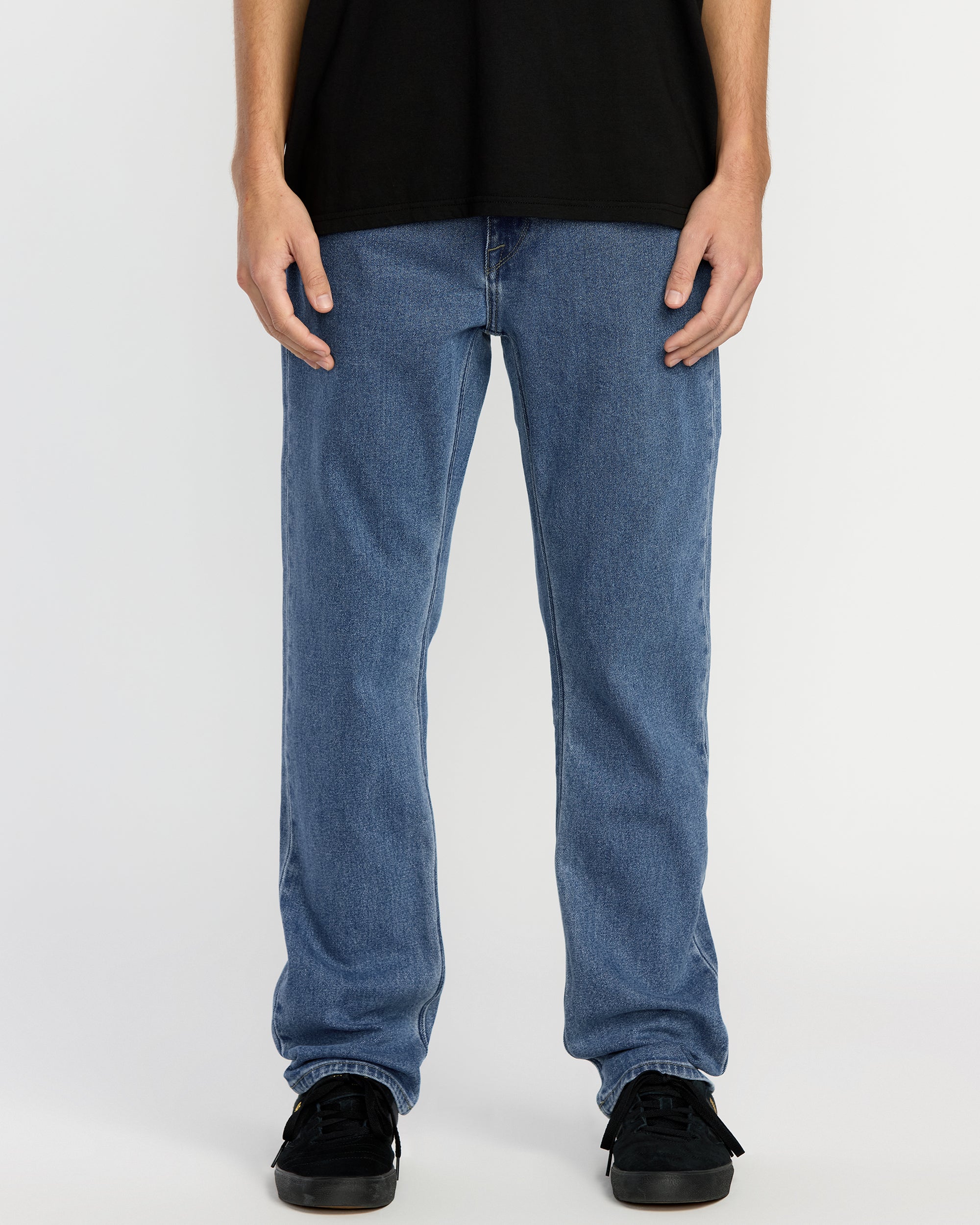 A person wearing a black t-shirt, Men's Solver Denim in Deep River Blues, and black sneakers stands against a plain white background. The image is cropped from the shoulders down.