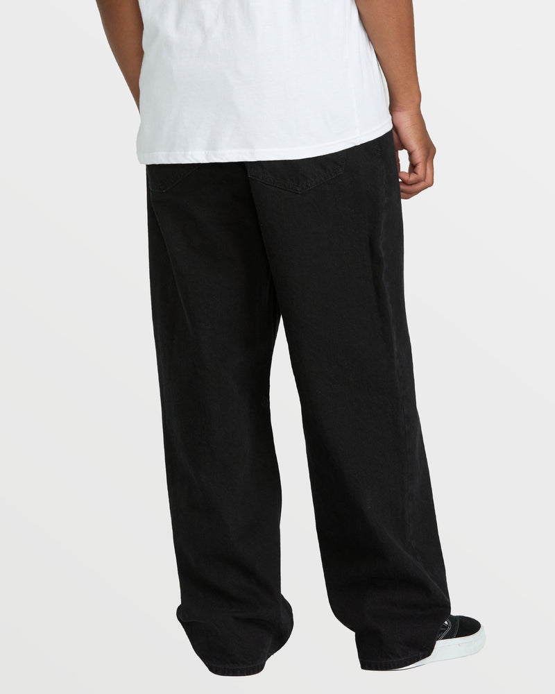 A person wearing Volcom Men's Billow Denim, a loose fit style featuring classic black pants.