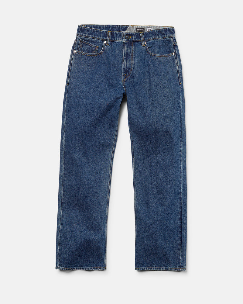 The Volcom Men’s Pipe Dreams Denim Pants, crafted from rigid 100% cotton, feature a relaxed straight fit with five pockets, button and zipper closure, and subtle thigh fading. These dark indigo jeans are shown laid flat on a white background.