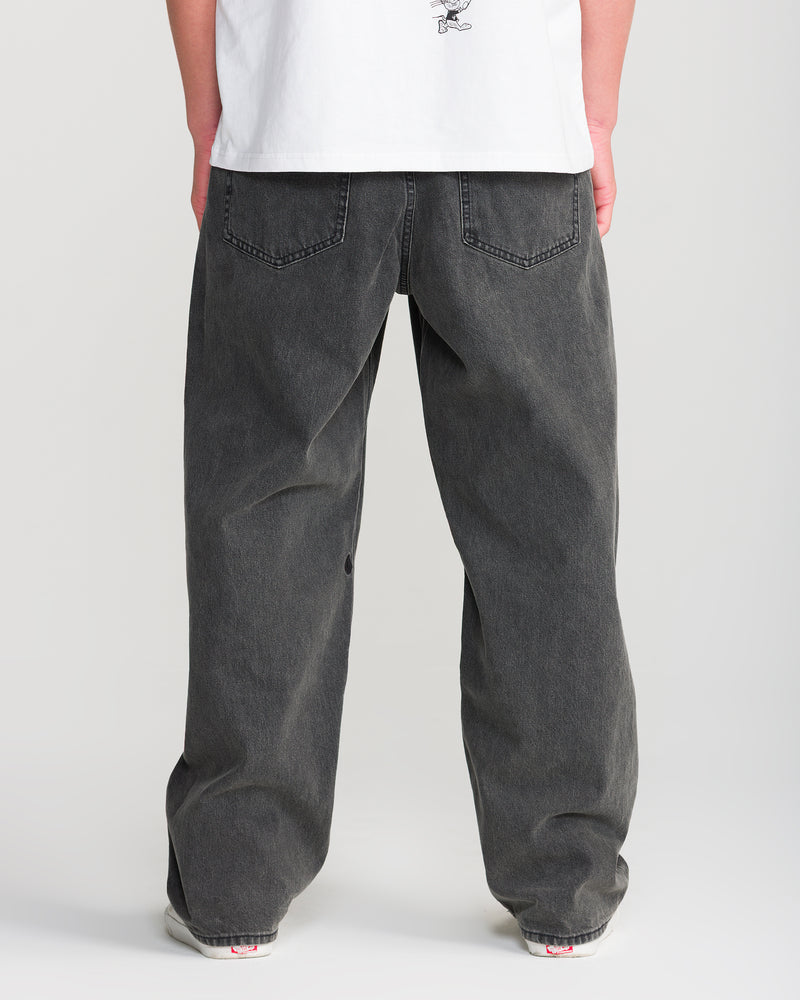 Person wearing a white shirt and Volcom Men’s Billow Denim loose fit black jeans with back pockets, standing with their back to the camera on a plain background.