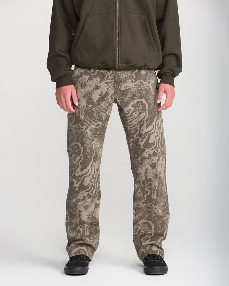 A person wears Volcom Men’s Kinkade Utility Denim and a dark green zip-up hoodie, standing facing forward with hands at their sides; only the lower half of their body is visible.