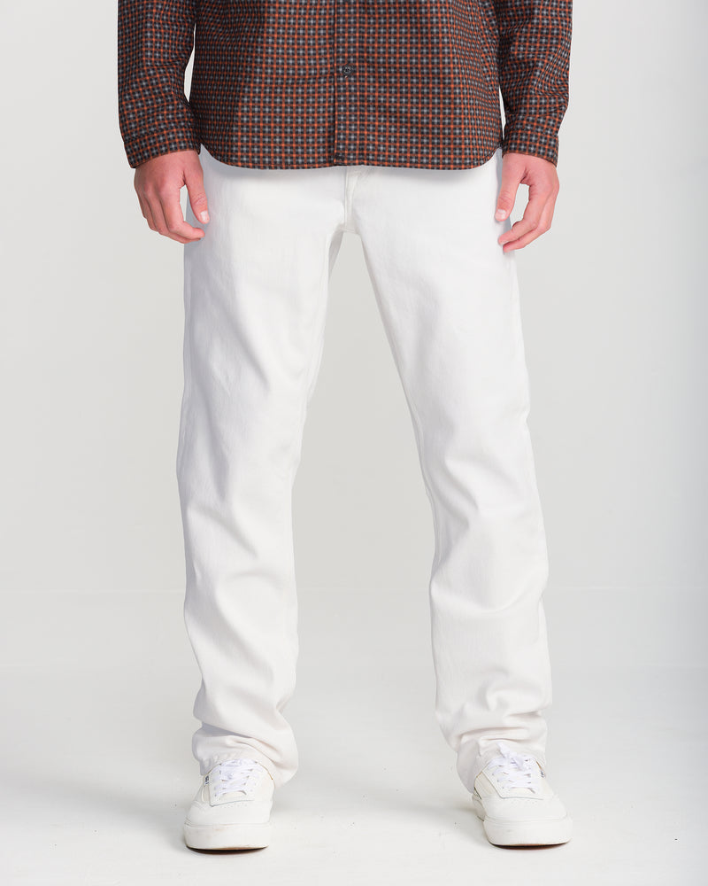 A person wearing a checkered button-down shirt, white Men’s Solver Denim, and white sneakers.