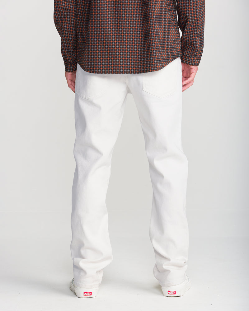 A person seen from the back wearing white straight leg Volcom Men’s Solver Denim jeans and a long-sleeved patterned shirt.