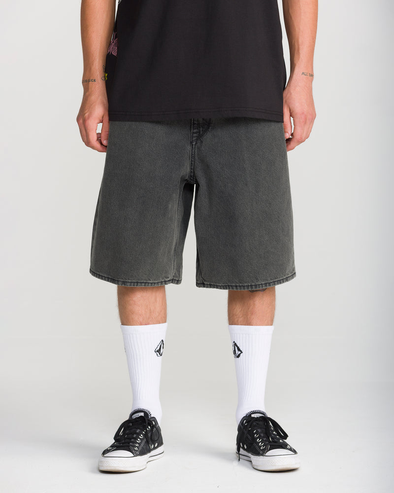 A person wearing loose-fit Men’s Billow Denim Short 22, white crew socks, and black sneakers.