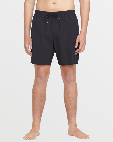 A person stands barefoot against a white background wearing Volcom Men's Truly Liberators black 17-inch trunk swim shorts with a drawstring waist and side cargo pocket; their upper body is mostly out of frame.