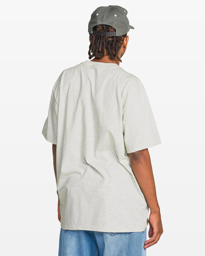 A person with medium skin tone is shown from the back, wearing a light grey Volcom Men's Eurobox Short Sleeve Tee, light blue jeans, and a grey baseball cap against a plain white background.