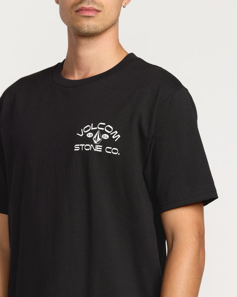 A man wears the Volcom Men's Always Ripping Short Sleeve Tee, classic fit in black premium ring spun cotton, featuring "VOLCOM STONE CO." and logo in white on the left chest. Background is plain white.