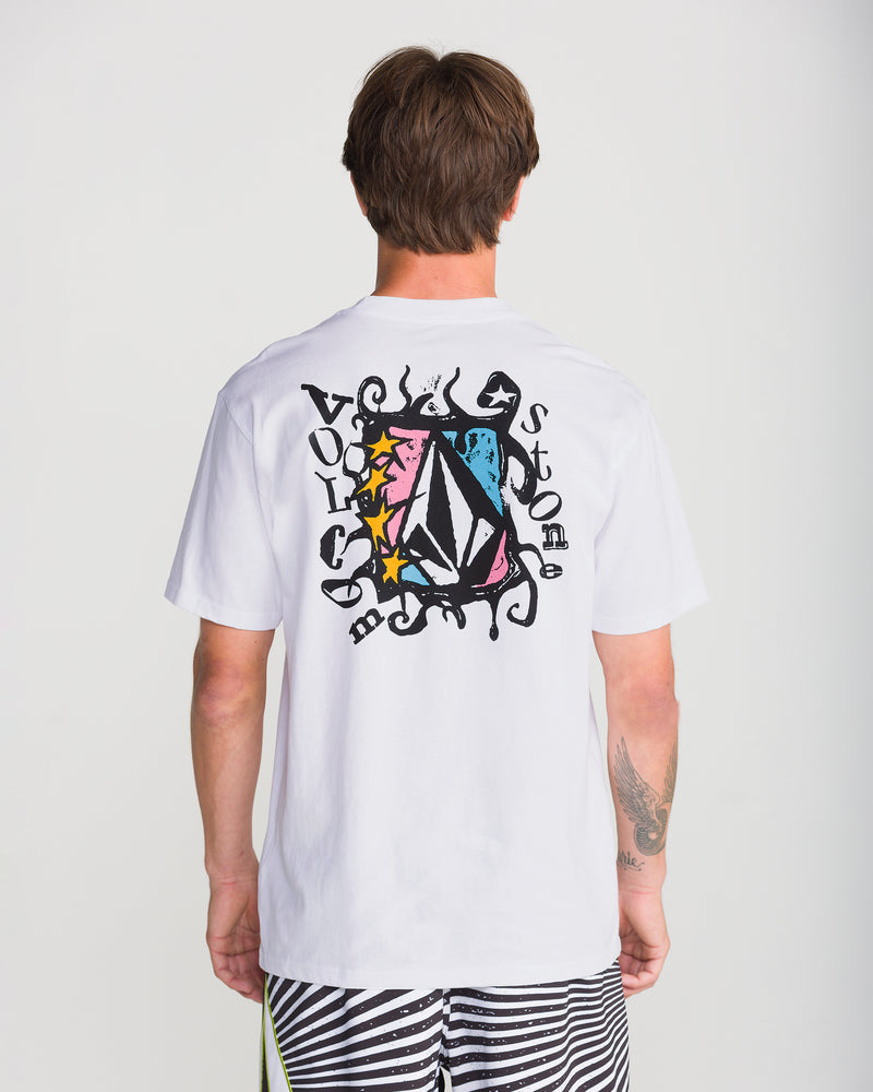 A person wearing the Volcom Men’s Framer Short Sleeve Tee with a vibrant geometric and star design, black lettering, back patterns, and paired with black and white striped shorts.