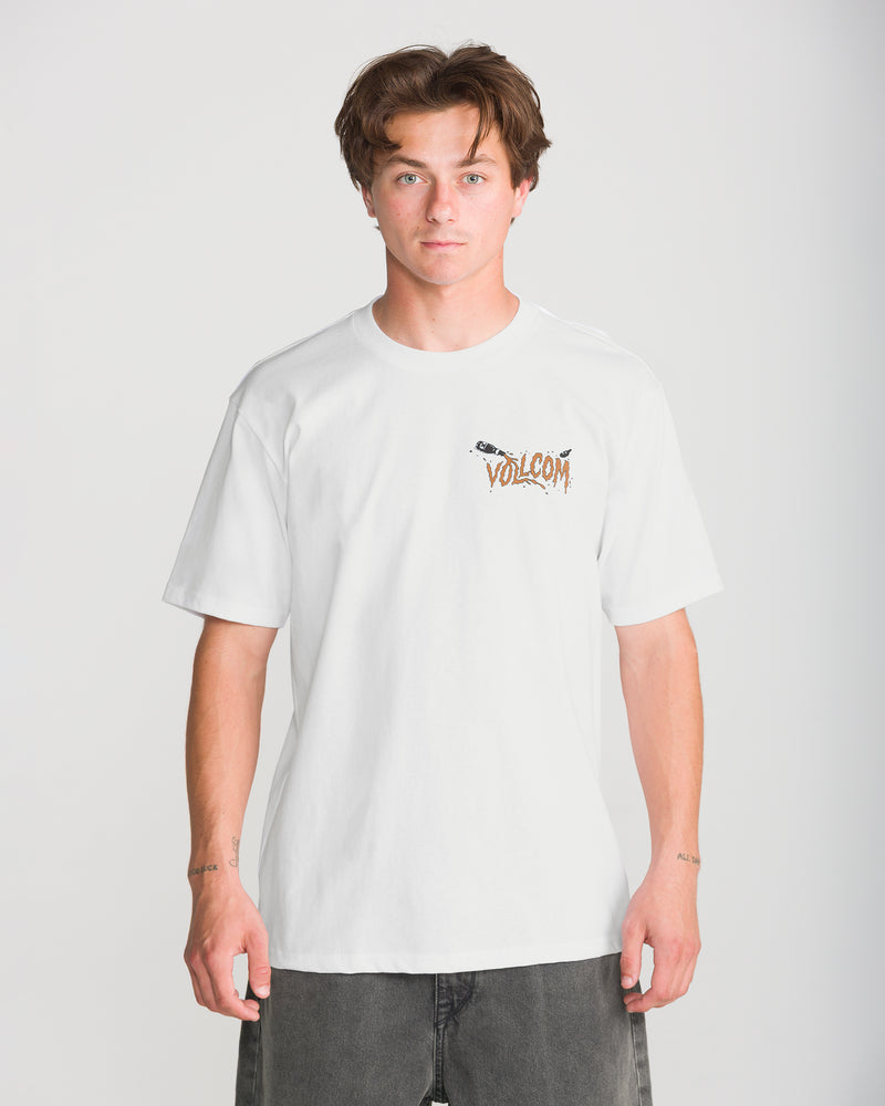 A young man with brown hair wears the Volcom Men’s Zombeach Short Sleeve Tee and dark jeans, standing against a plain light gray background and looking directly at the camera with a neutral expression.