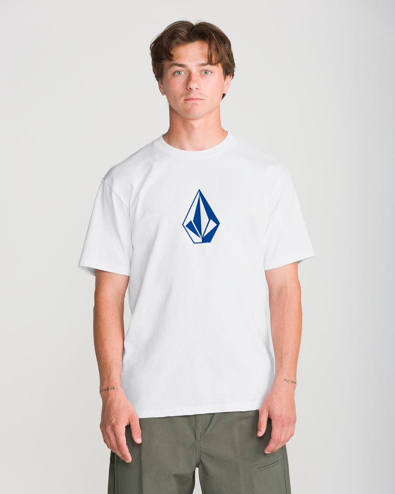 A person wears a Men’s Full Stone Short Sleeve Tee featuring a blue diamond-shaped logo on the chest.