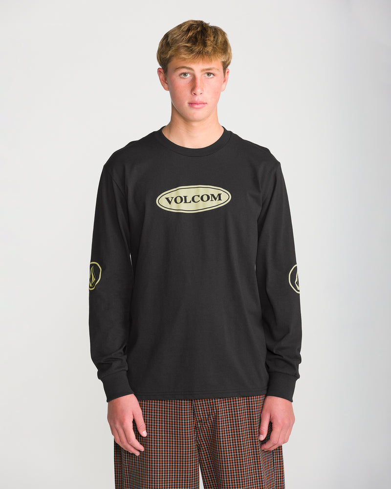 A person wears a black Volcom Men’s Remastered Stone Long Sleeve Tee, featuring a heavyweight, classic fit, a tan oval logo on the chest, and matching circular logos on each sleeve.