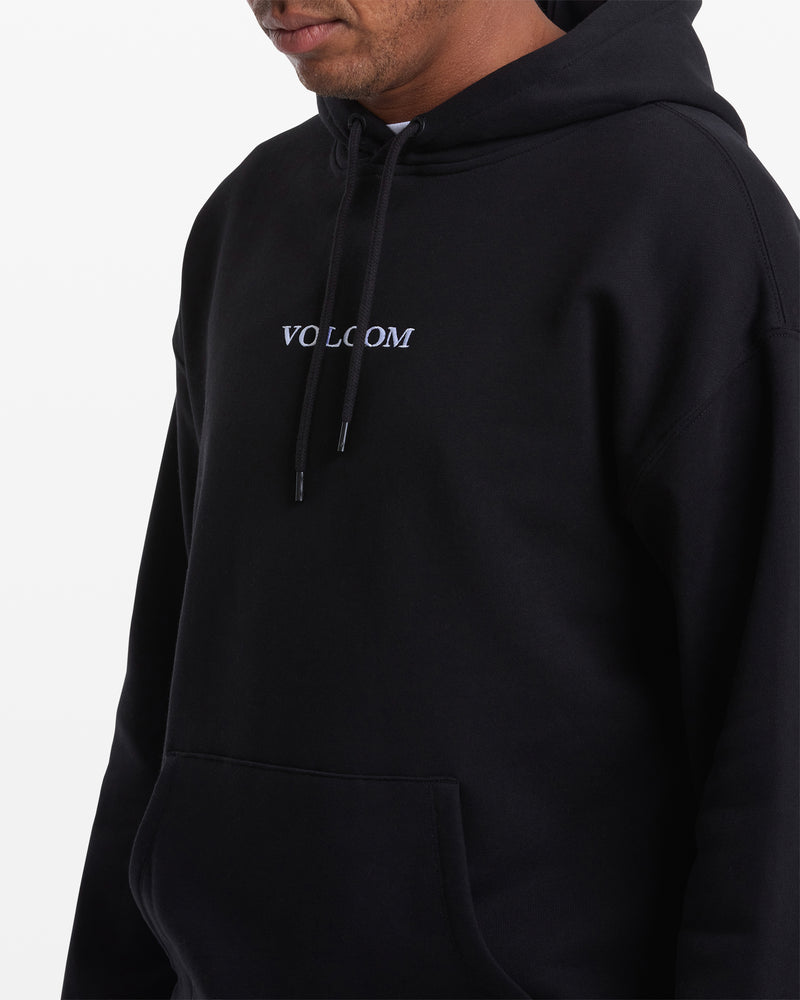 A man wears the Volcom Men's Stone Pullover—black, hooded, with "VOLCOM" embroidered in white on the front. Made from BCI cotton, only his upper body is shown, with hands tucked into the sweatshirt pocket.