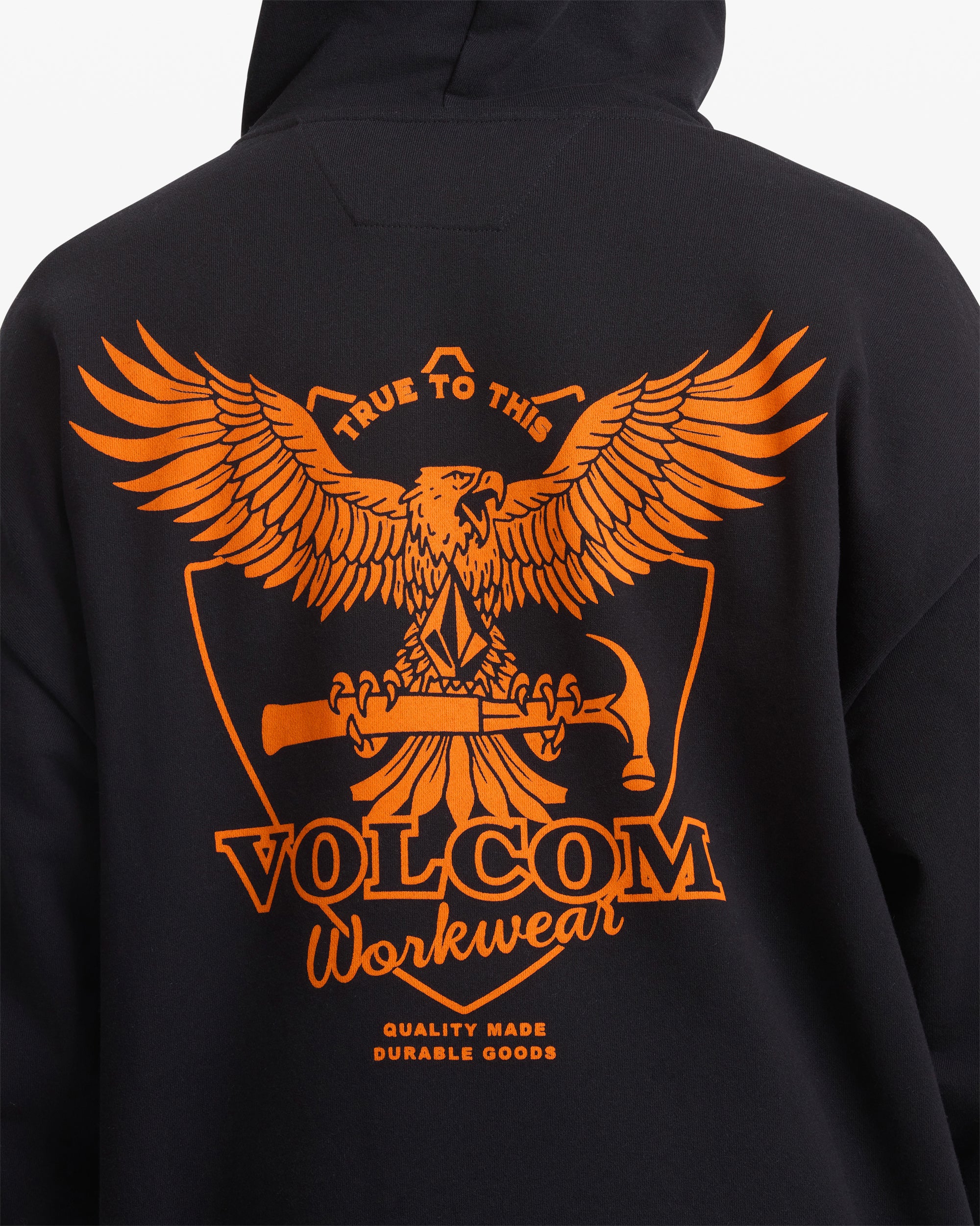 A man is wearing the Volcom Men's Hammered Pullover, a black jacket featuring an orange eagle design.