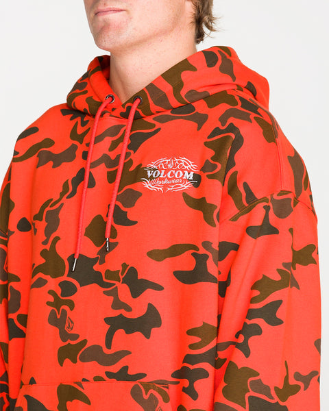 A person wearing the Volcom Men’s Talon Workwear Pullover in red and black camouflage, with the hood down, is seen from the chest up against a plain background. This drop-shoulder hoodie features a relaxed fit for everyday comfort and versatile style.