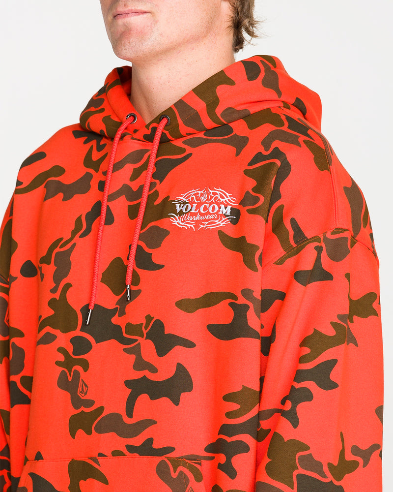 A person wearing the Volcom Men’s Talon Workwear Pullover in red and black camouflage, with the hood down, is seen from the chest up against a plain background. This drop-shoulder hoodie features a relaxed fit for everyday comfort and versatile style.