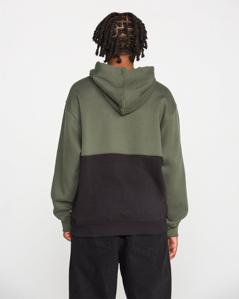 A person with braided hair is seen from behind against a plain white background, wearing the Volcom Men's Long Division Pullover. The hoodie showcases green and black colorblocked panels and is paired with black pants. Crafted with REPREVE recycled fibers, this eco-conscious pullover combines style and sustainability.