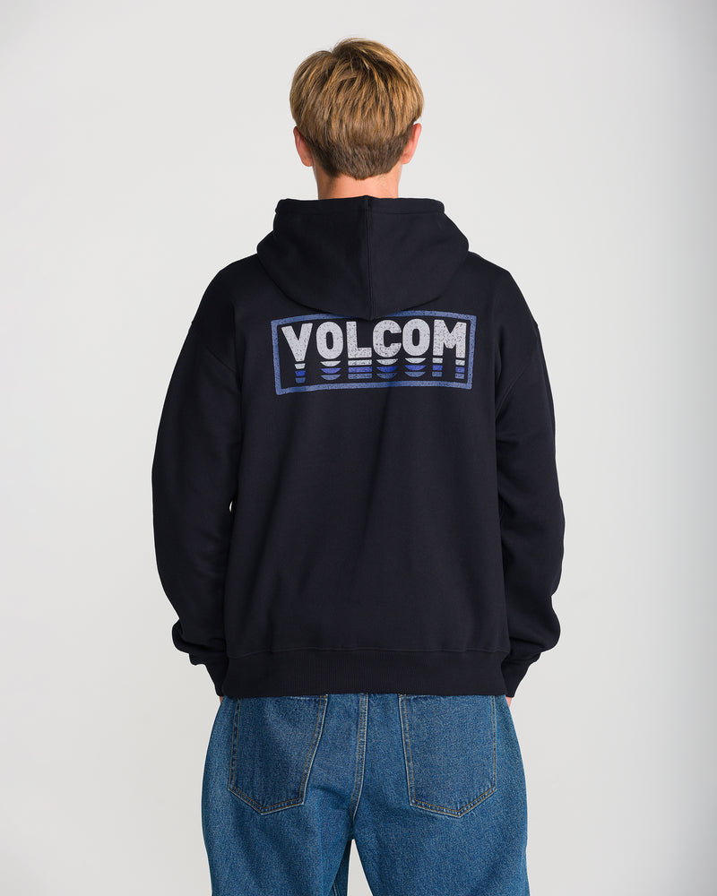 A person in blue jeans and a black Men’s Quadratic Pullover by Volcom, featuring brushed-back fleece and large VOLCOM letters on the back, stands with their back to the camera.