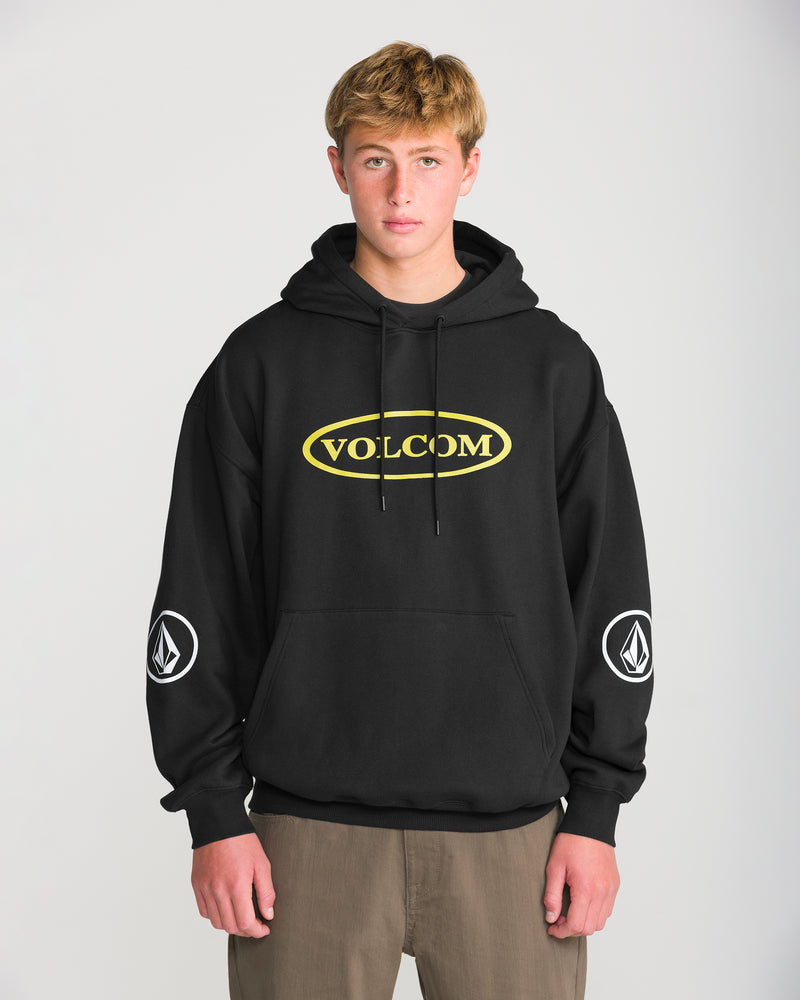 A man wearing a black Volcom Men’s Remastered Stone Pullover with a yellow oval logo on the chest and a circular emblem on each sleeve.