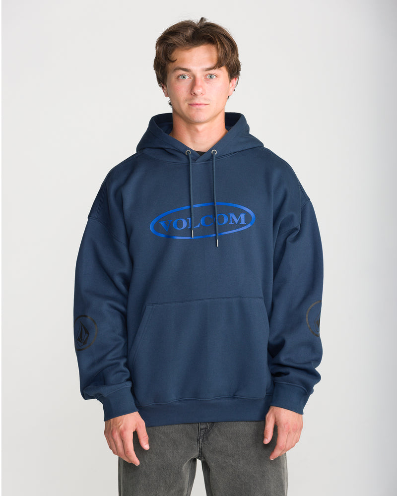 A man wearing a navy blue Men’s Remastered Stone Pullover in brushed-back fleece, featuring a blue oval logo graphic on the chest and a small emblem on the sleeve.
