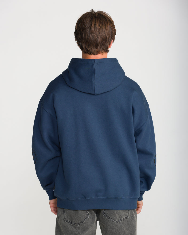Back view of a person wearing a navy blue Men’s Remastered Stone Pullover in brushed-back fleece and grey jeans.