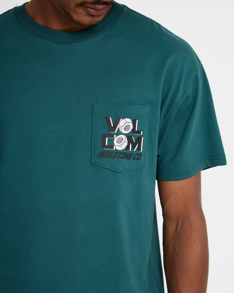 A person wearing the Volcom Men's Parted Out Pocket Short Sleeve Tee in teal, featuring a chest pocket with the Volcom Stone Co. logo in black, white, and gray.
