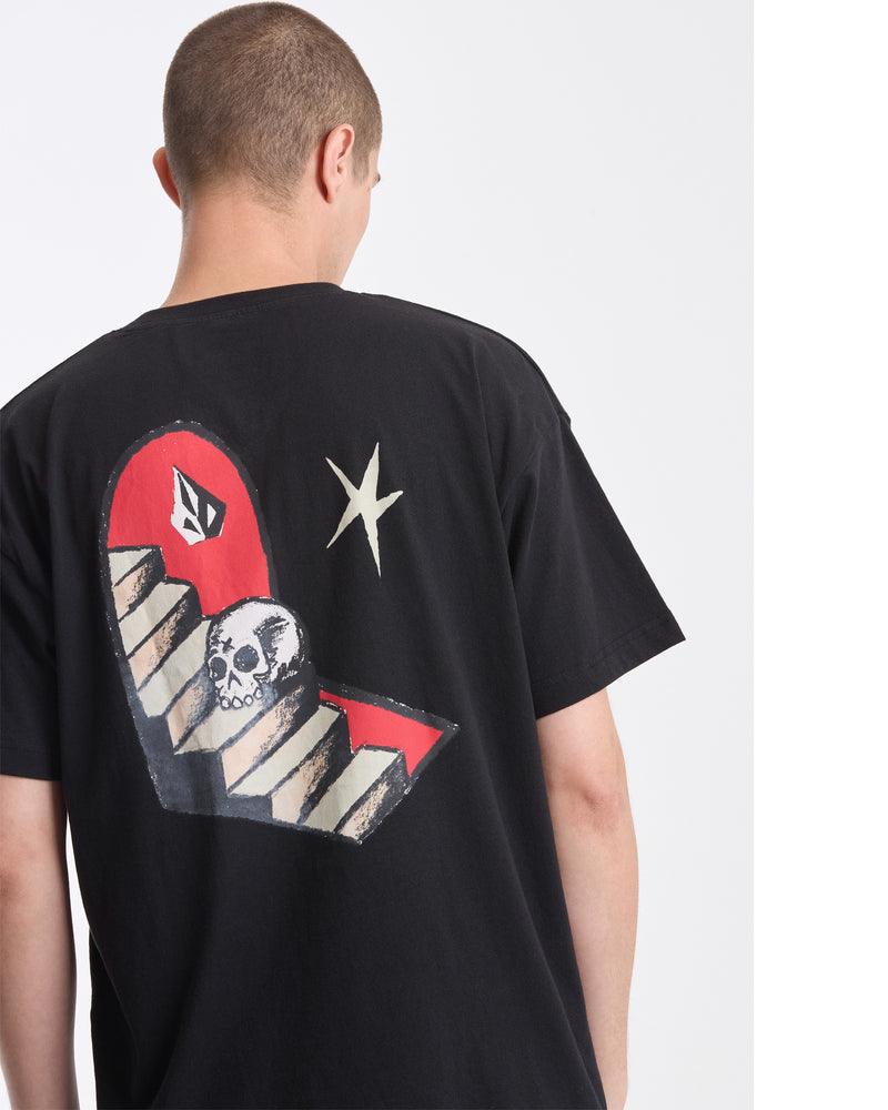 A person with short hair, seen from behind, wears the Volcom Men's Featured Artist Seth Conboy Loose Short Sleeve Tee with graphic art in red, white, and beige. The background is plain white.