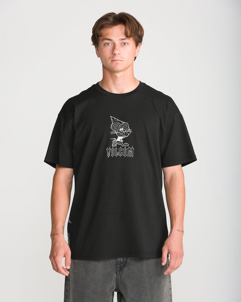 A man wears a black Men’s Featured Artist Casey Jones Short Sleeve Tee by Volcom, featuring a white line-art graphic of a cartoon cat in a pizza-slice hat above gothic-style text.