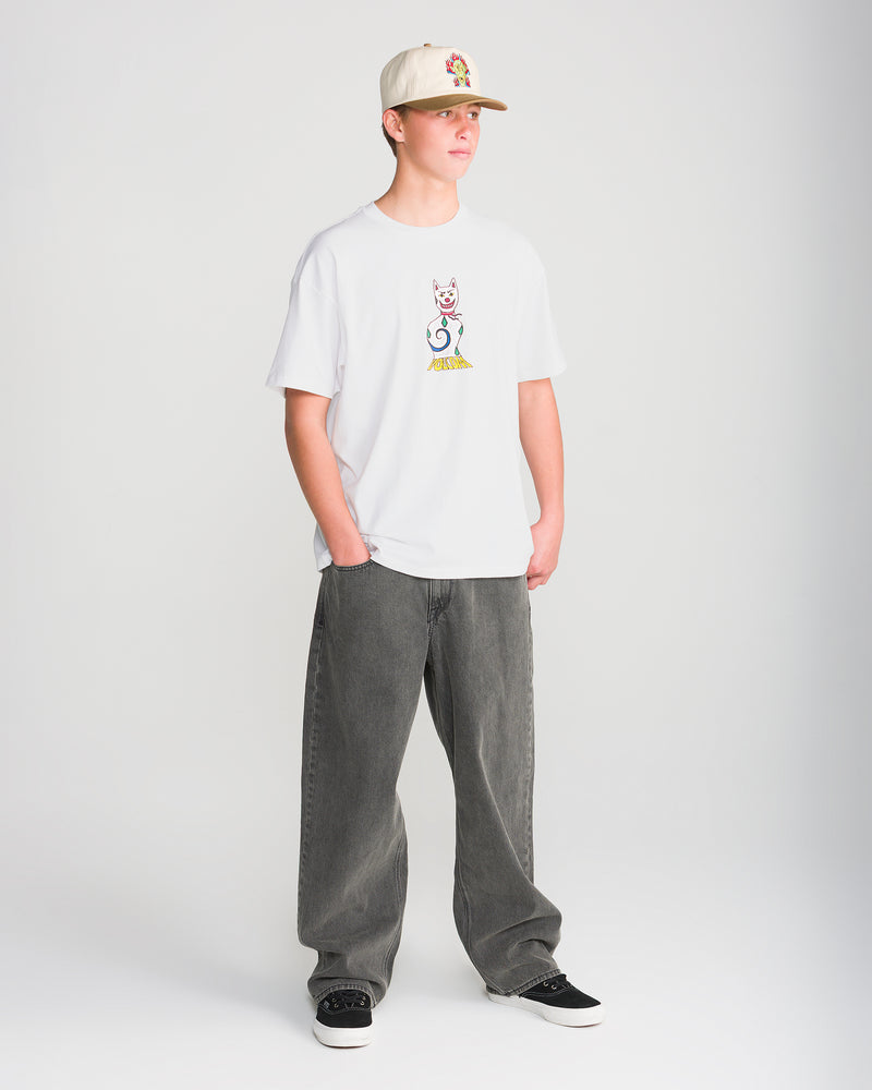 A person wearing a white Volcom Men’s Featured Artist Casey Jones Short Sleeve Tee with a colorful cat graphic, baggy grey jeans, black sneakers, and a tan baseball cap.