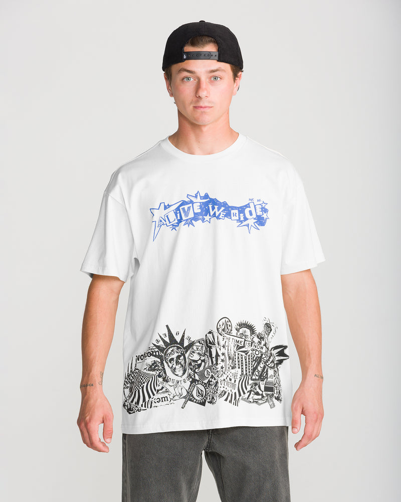 A person wears a white Volcom Men’s Alive We Ride Short Sleeve Tee, featuring a loose fit, blue Alive We Ride text on the chest, and a black-and-white graphic collage of figures and symbols at the hem.