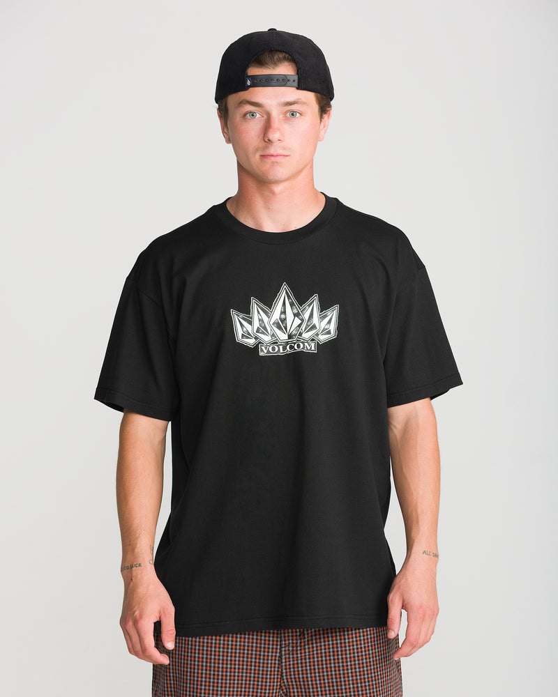 A man wearing a black Men’s Tooms Short Sleeve Tee with a white stone-shaped logo on the chest and a black baseball cap.