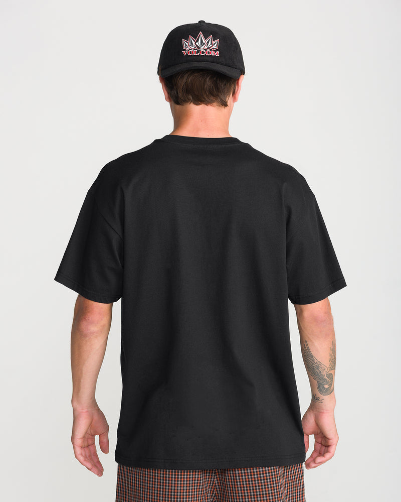 A person seen from behind wearing a plain black heavyweight cotton Volcom Men’s Tooms Short Sleeve Tee and a black baseball cap with a graphic logo.