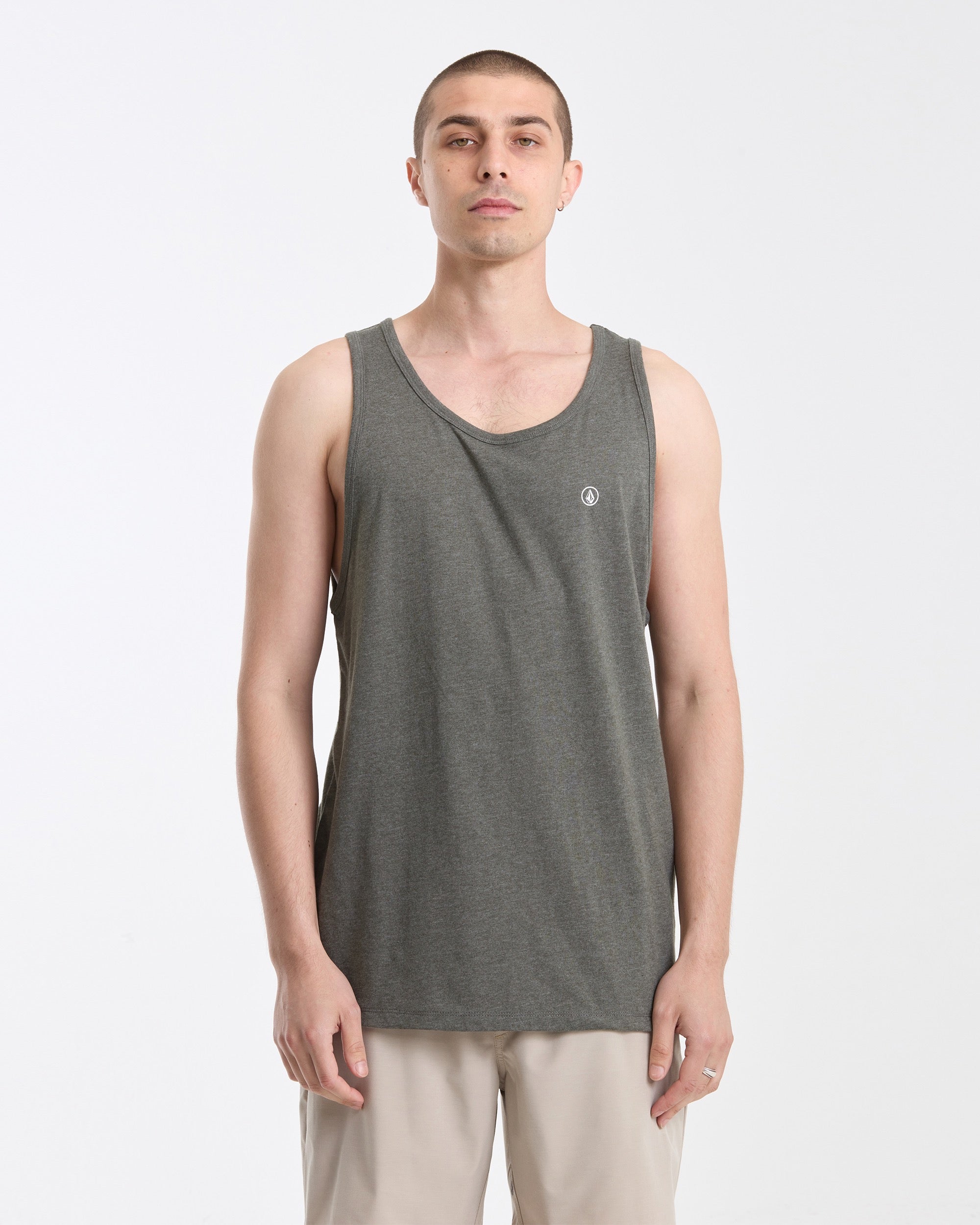 A person with short hair wears the Volcom Men's Solid Heather Tank in gray and light beige pants, standing against a white background and looking directly at the camera with a neutral expression.