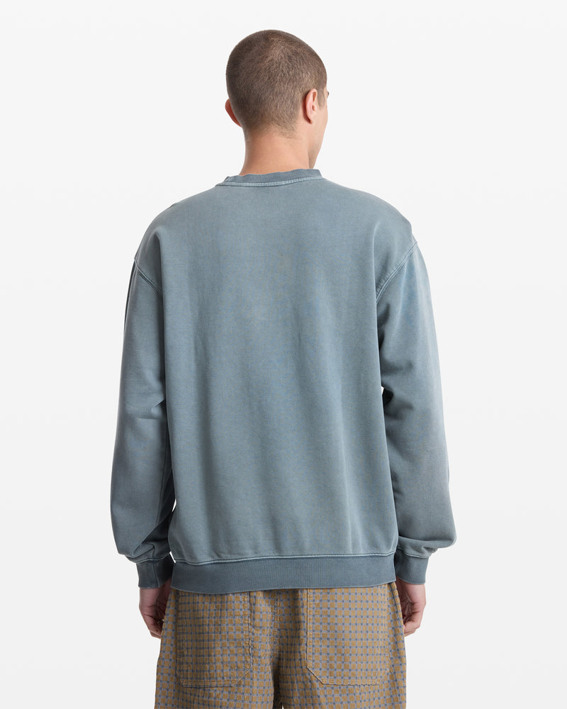 A person with short hair, seen from behind, wears the Volcom Men's Smoothie Crew sweatshirt in faded blue-gray and light brown patterned shorts against a plain white background.