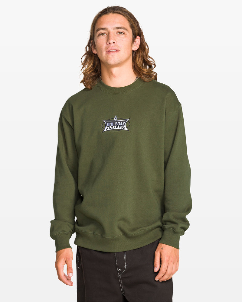 A person with long brown hair wears the Volcom Men's Stone Cruiser Crew in Squadron Green, featuring a small white and black logo on the chest, paired with black pants, standing against a plain white background.