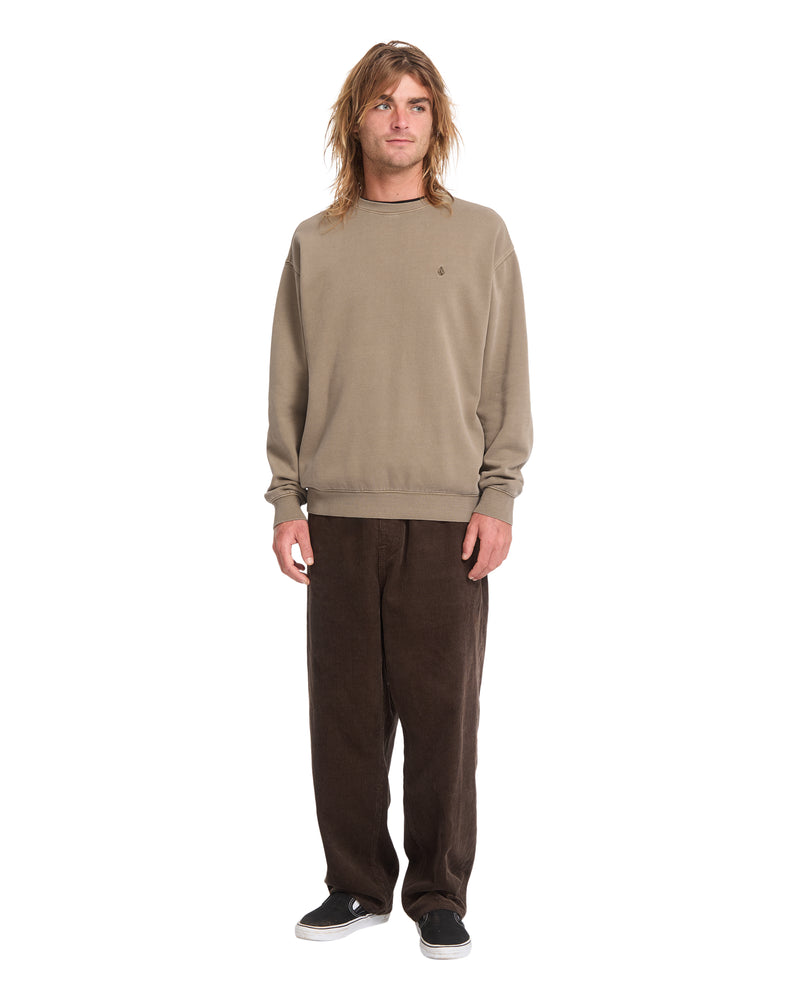 A person wearing a Volcom Men’s Single Stone Power Wash Crew heavyweight cotton-blend fleece sweatshirt, brown trousers, and black slip-on shoes.