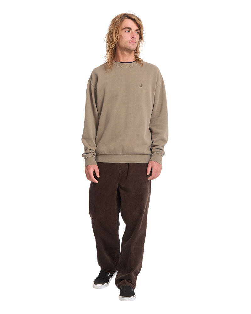 A man wearing a tan Volcom Men’s Single Stone Power Wash Crew heavyweight cotton-blend fleece sweatshirt and dark brown corduroy pants.