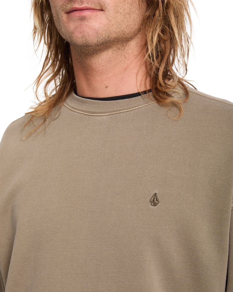 A person wearing a tan Volcom Men’s Single Stone Power Wash Crew, a heavyweight cotton-blend fleece sweatshirt with a small embroidered logo on the chest.