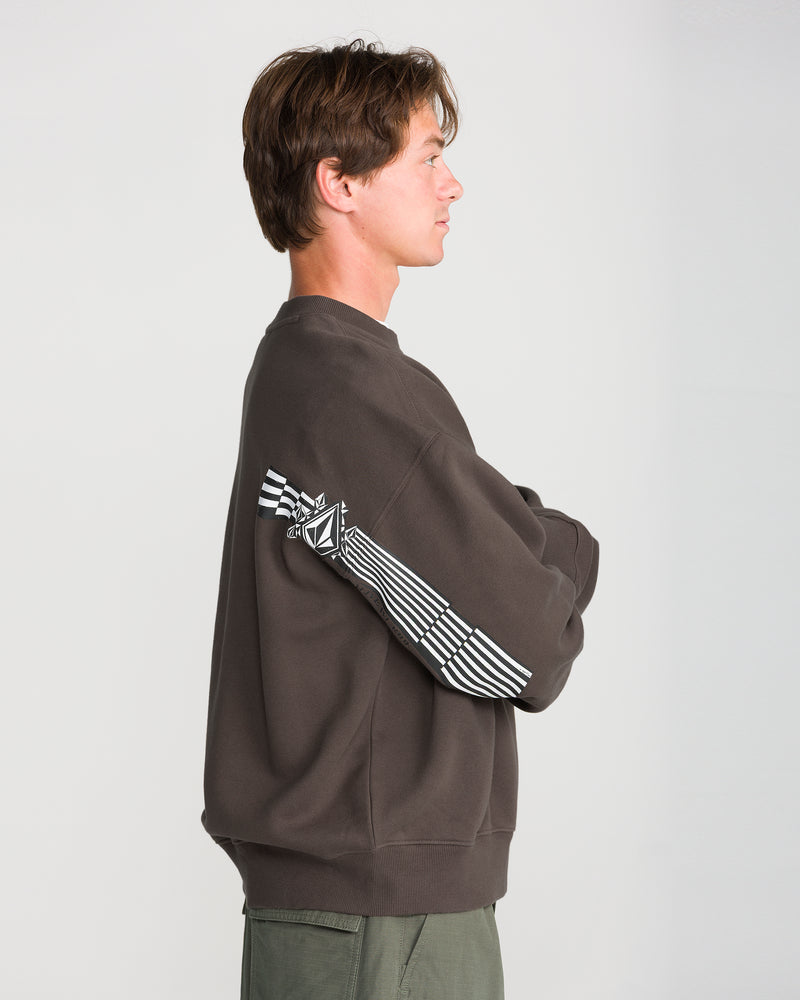 A man in profile wears a dark gray Men’s Stone Op Crew fleece, featuring a white geometric Volcom logo and striped graphics on the sleeve.