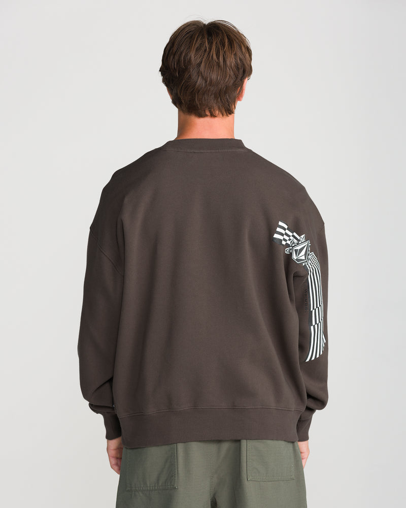 A person seen from the back wearing a Men’s Stone Op Crew, a boxy fit, dark brown crewneck sweatshirt featuring Volcom graphics, including a diamond logo and checkerboard patterns on the right sleeve.