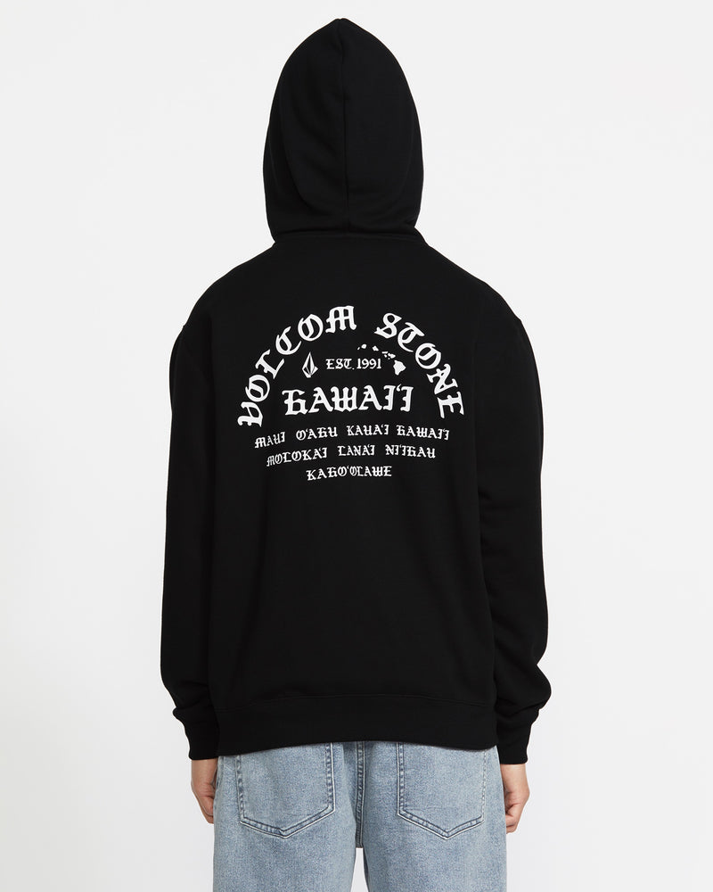 A man wears the Volcom Men's Lineage Zip Fleece, a black relaxed-fit hoodie with "Volcom Stone Hawaii" and smaller white text on the back. He stands facing away from the camera against a white background.