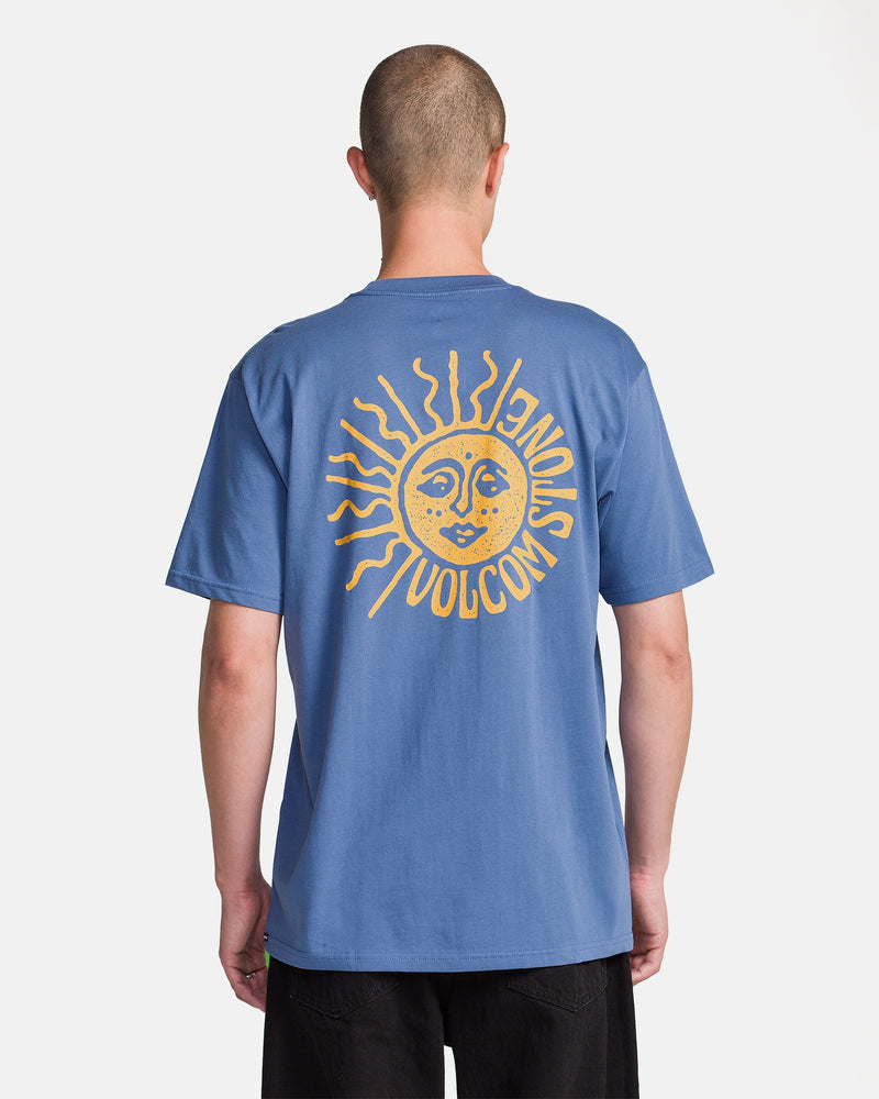 A man models the Volcom Men's Mazatlan Short Sleeve Tee, featuring a large yellow sun graphic with stylized VOLCOM text on the back, set against a plain white background.